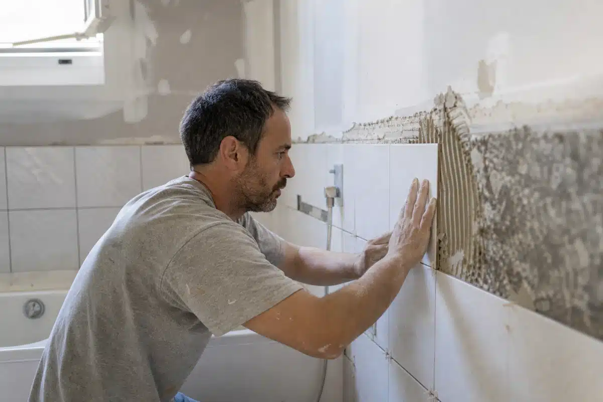 Homme en train de poser du carrelage mural